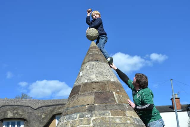 Finnbar Reilly 5 with help from his dad Cahal Reilly at the butter cross on Easter Monday in Hallaton.
PICTURE: ANDREW CARPENTER