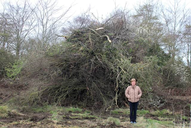 Sue Bourne with one of two heaps of bushes cut down.