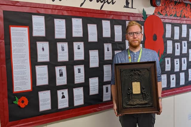 teacher Lee Holmes by their WWI display - and the memorial plaque.
