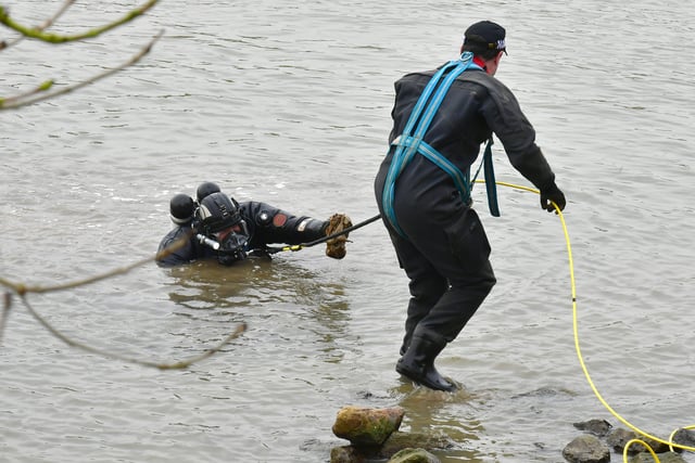 A police diver hands an object discovered in the river to a colleague. EMN-220203-142943001