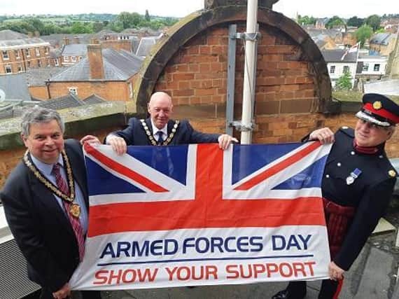 Pictured holding the flag (l-r) HDC vice chairman Cllr Neil Bannister, HDC chairman Stephen Bilbie, and Richard Clowes Esq, deputy lieutenant.