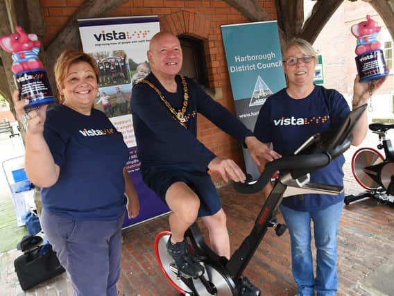 Harborough District chairman Stephen Bilbie with Lisa Harrison-Byrne and Ester Blunt of Vista during his charity cycle ride under the Old Grammar School.
PICTURE: ANDREW CARPENTER
