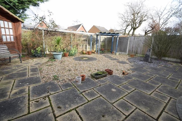 A second view of the rear garden. There is a stone water feature, landscaped and gravelled areas, and attractive shrub and plant borders. The front garden is also low-maintenance and hard landscaped, with gravel features and shrubs.