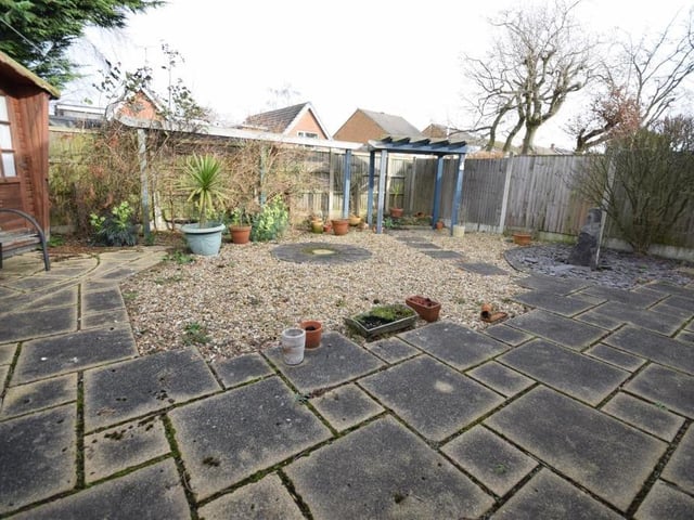 A second view of the rear garden. There is a stone water feature, landscaped and gravelled areas, and attractive shrub and plant borders. The front garden is also low-maintenance and hard landscaped, with gravel features and shrubs.