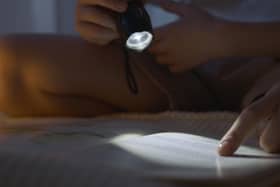 Reading by torchlight. Picture: Artem Podrez