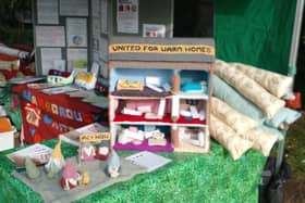 Volunteers for United for Warm Homes showcase their knitted home