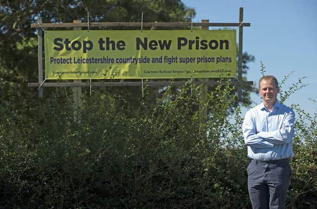 Neil O'Brien MP with an opposition banner outside Gartree prison. PICTURE: ANDREW CARPENTER