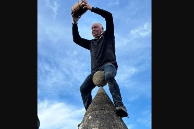 Committee chairman Phil is lifted onto the stone Butter Cross.