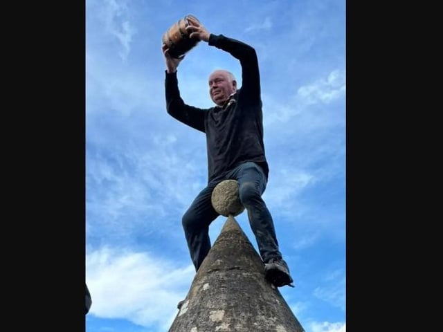 Committee chairman Phil is lifted onto the stone Butter Cross.