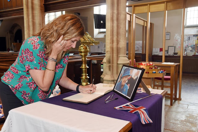 Stacey Barthorpe leaves a message in the book of condolence for the Queen at St Dionysius church in Market Harborough.