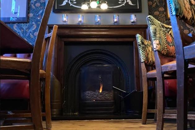 A fireplace with a mirror promoting Kelham Island Brewery.